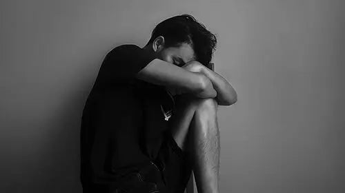 Black and white photo of person sitting with head down, illustrating emotion impact of odors on cognition